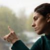 Woman touching window with finger raining outside
