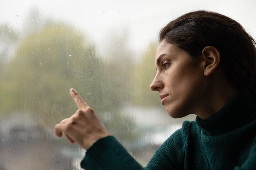 Woman touching window with finger raining outside